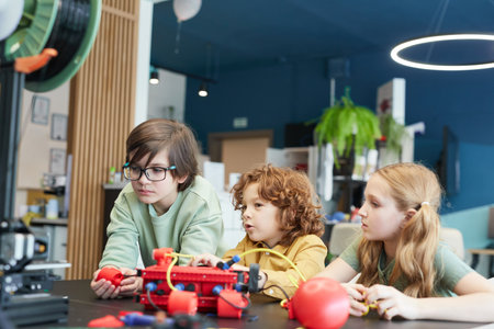 Portrait of three children operating robots during engineering class at modern school, copy spaceの写真素材