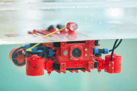 Background image of red robotic boat with camera in water tank, copy space