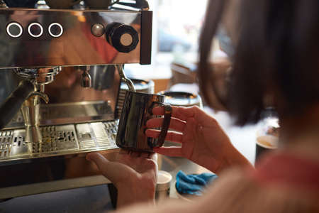 Close up of female barista making fresh coffee in cafe or coffee shop and pouring cream in latte, copy spaceの写真素材