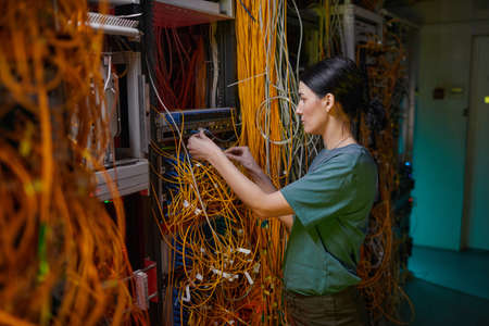 Side view portrait of young woman wearing military uniform inspecting server while working in server...