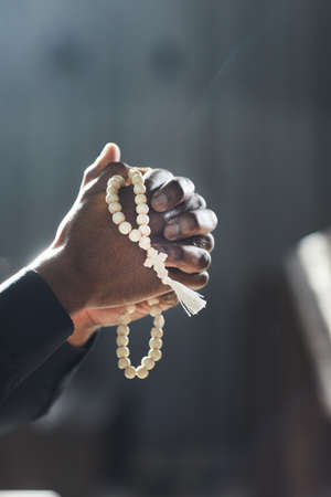 Close-up of African priest holding rosary and praying