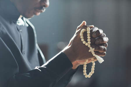Close-up of African man holding beads in his hands and praying in the churchの写真素材