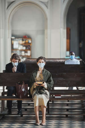 Young woman sitting on the bench and reading the Bible during massの写真素材