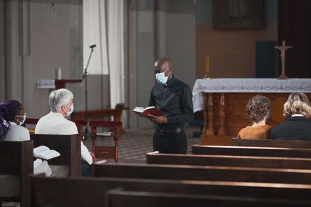 People sitting during Sunday mass in the church and listening to priestの写真素材