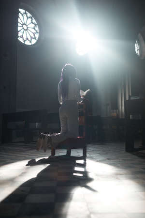 Rear view of woman reading the prayers sitting in chair in the churchの写真素材
