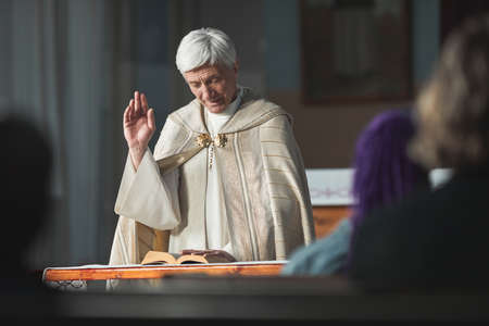 Senior priest reading the Bible for people during ceremony in the churchの写真素材
