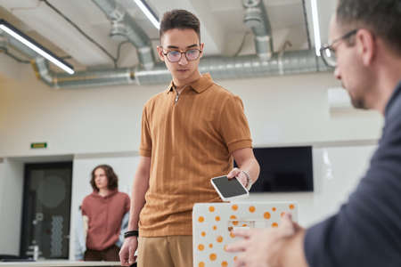 Portrait of teenage boy putting smartphone in box in no gadget classroom at school, copy spaceの写真素材