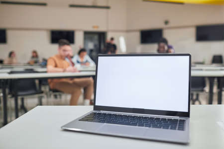 Background image of opened laptop with blank white screen on t5eachers desk in school auditorium, copy spaceの写真素材