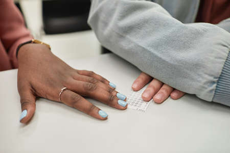 Close up of two unrecognizable students passing cheat note sneaking white taking exam in school,...