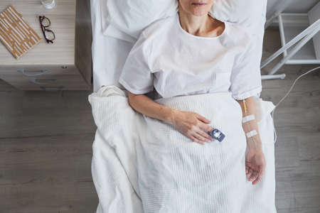 High angle view of sick patient lying on bed and recovering after operation at hospital