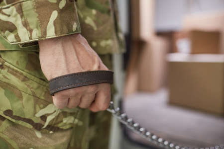 Close-up of military man holding leash in his hand and walking with dog
