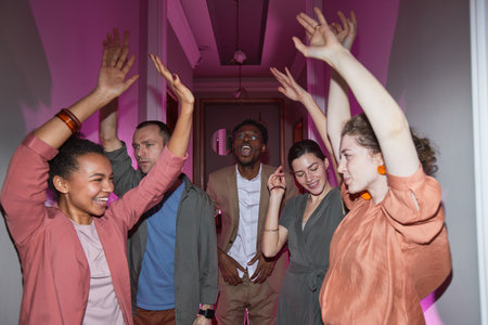 Diverse group of carefree people dancing while enjoying house party indoors, shot with flash