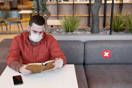Portrait ofadult man wearing mask while working at table in cafe