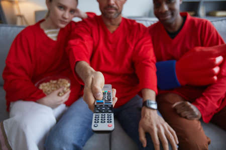 Close up of sports fans holding remote control while watching game match at home, copy space