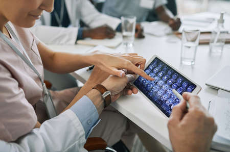 Close up of doctors looking at X-ray images on display during medical council in conference room,...