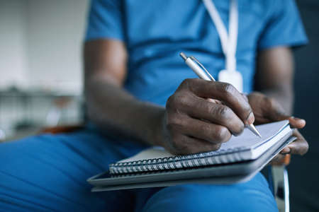 Close up of unrecognizable African-American doctor taking notes while attending medical conference...