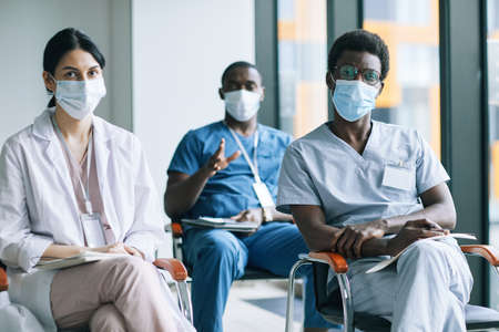 Diverse group of doctors wearing masks while attending medical conference or seminar