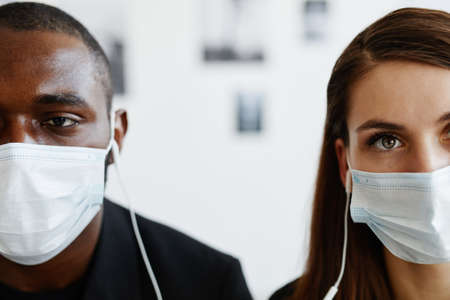 Graphic close up of couple in art gallery wearing masks and listening to audio guide, focus on eyesの写真素材