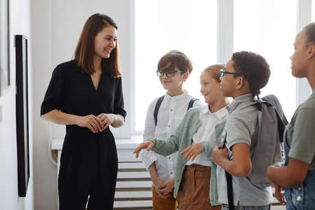 Diverse group of children listening to female tour guide while visiting modern art gallery, copy spaceの写真素材