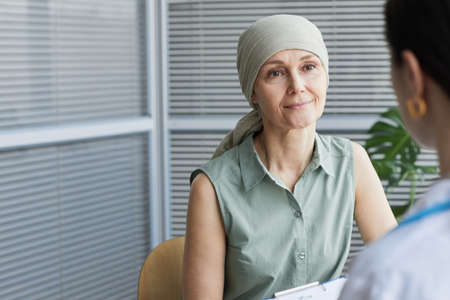 Portrait of mature woman smiling while talking to female doctor during consultation in clinic, copy...