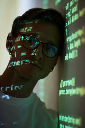 Portrait of IT manager in eyeglasses looking at camera while standing near the white board with...