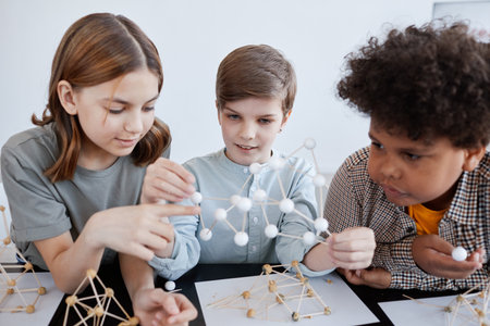 Group of three children playing with wooden models during art and craft class in schoolの写真素材