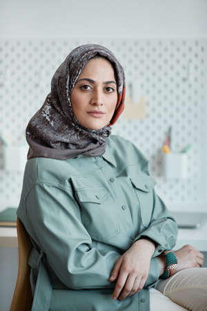 Vertical portrait of confident Middle-Eastern woman wearing headscarf in office and looking at cameraの写真素材