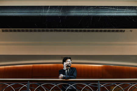 Graphic wide angle portrait of successful Middle-Eastern businessman speaking by smartphone while standing on balcony in luxurious hotel, copy spaceの写真素材