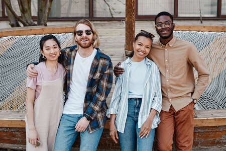 Diverse group of young people posing outdoors in urban city setting and smiling at cameraの写真素材