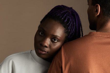 Close up portrait of young African-American woman looking at camera while leaning on boyfriend...