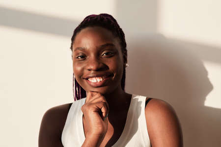 Portrait of smiling African-American woman looking at camera while posing against white in graphic...