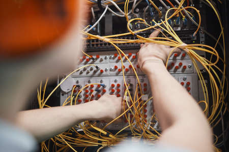 Close up of network engineer connecting cables in server room during maintenance work in data center, copy spaceの写真素材