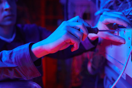 Close up of man setting up computer network in server room with cables and wires, copy spaceの写真素材