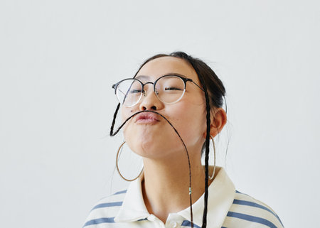 Minimal close up portrait of carefree teenage girl having fun and making faces while standing against white background, copy spaceの写真素材