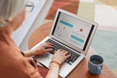 High angle portrait of modern senior woman using laptop while working from home and planning monthly schedule, copy spaceの写真素材