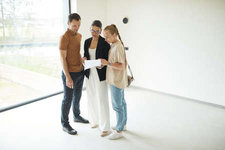 Minimal full length portrait of female real estate agent wearing mask while giving apartment tour to...