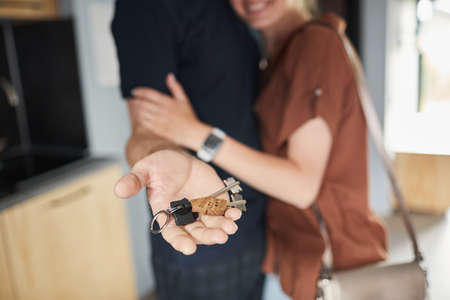 Close up of happy couple buying new house focus on male hand holding keys, copy spaceの写真素材