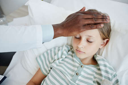 Close up of African-American doctor caring for little girl lying in hospital bed