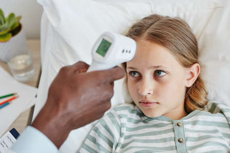 Close up of doctor checking temperature of child in hospital using infrared thermometer, copy spaceの写真素材