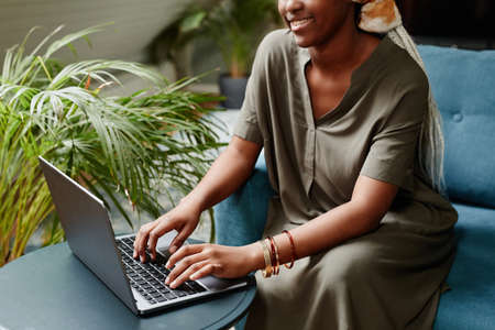 Cropped portrait of young African-American woman using laptop at home while working freelance, copy spaceの写真素材