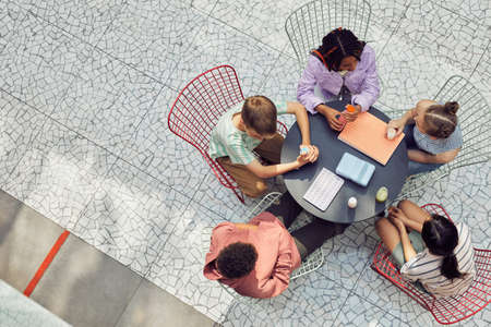 Graphic top down view at diverse group of kids sitting at table during lunch at modern school