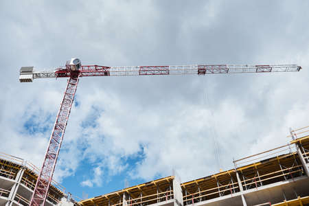 Low angle shot of residential building under construction with construction crane against blue sky,...