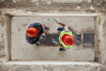 Top down view at two construction workers wearing hardhats at costruction site, copy spaceの写真素材