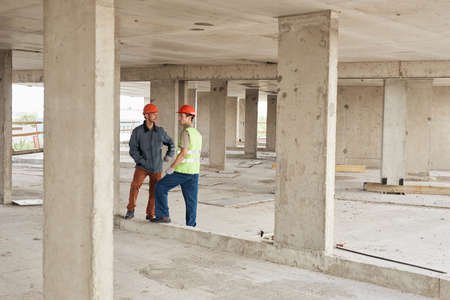 Full length portrait of two workers discussing engineering at costruction site, copy spaceの写真素材