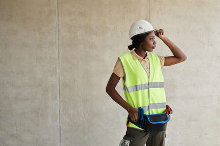 Waist up portrait of young African-American woman working at construction site and looking away, copy spaceの写真素材