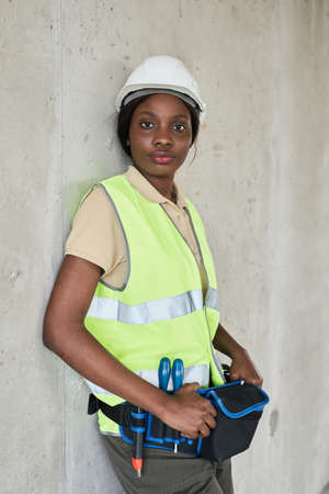 Vertical waist up portrait of young African-American woman working at construction site in engineeringの写真素材