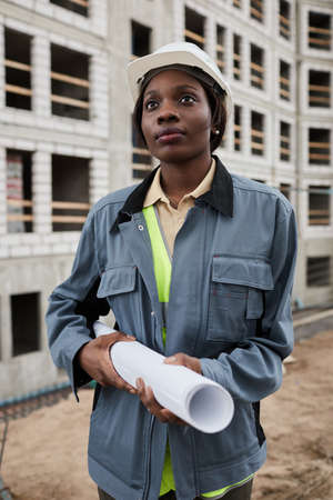 Vertical portrait of young female engineer posing at construction siteの写真素材
