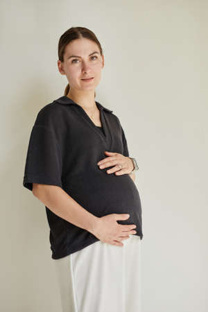 Portrait of content attractive pregnant middle-aged Caucasian woman in black and white comfortable...