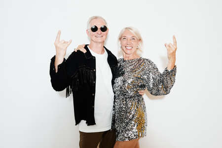 Waist up portrait of glamorous mature couple posing against white background at party, shot with flashの写真素材