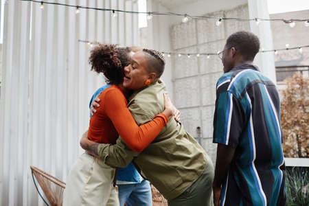 Multi-ethnic group of modern young people greeting each other at rooftop party, copy space